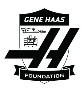 Gene Haas Foundation - shield with Gene Haas in top section, a race car and industrial equipment, and large stylized H. A ribbon that says Foundation is on the bottom of the shield